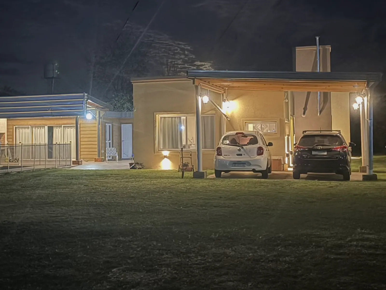 Cochera techada con dos autos en la quinta en Lobos, de noche