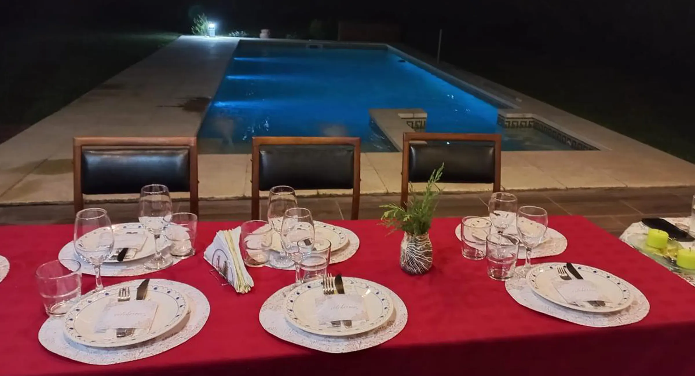 Mesa servida junto a la pileta de noche: quinta en Lobos para eventos
